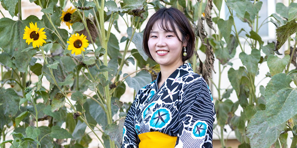 Miki Shono stands in front of sunflowers