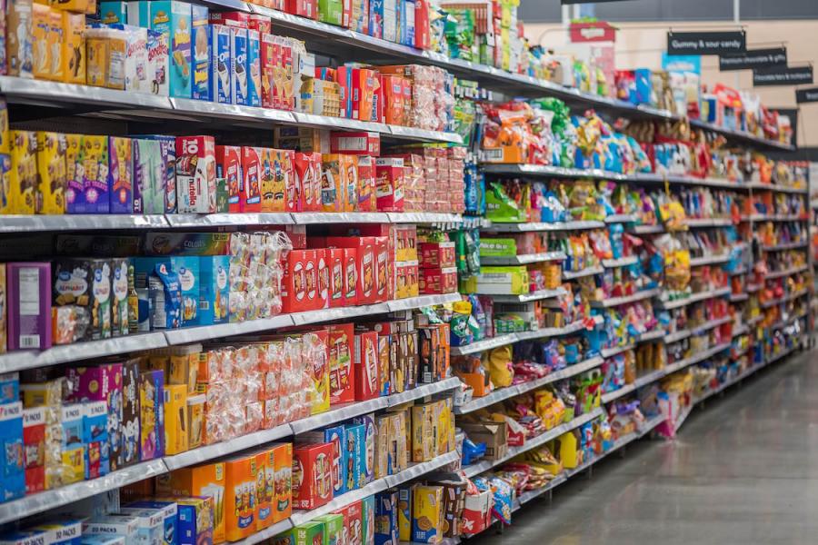 Cereals, crackers and other packaged goods are featured along a supermarket aisle.