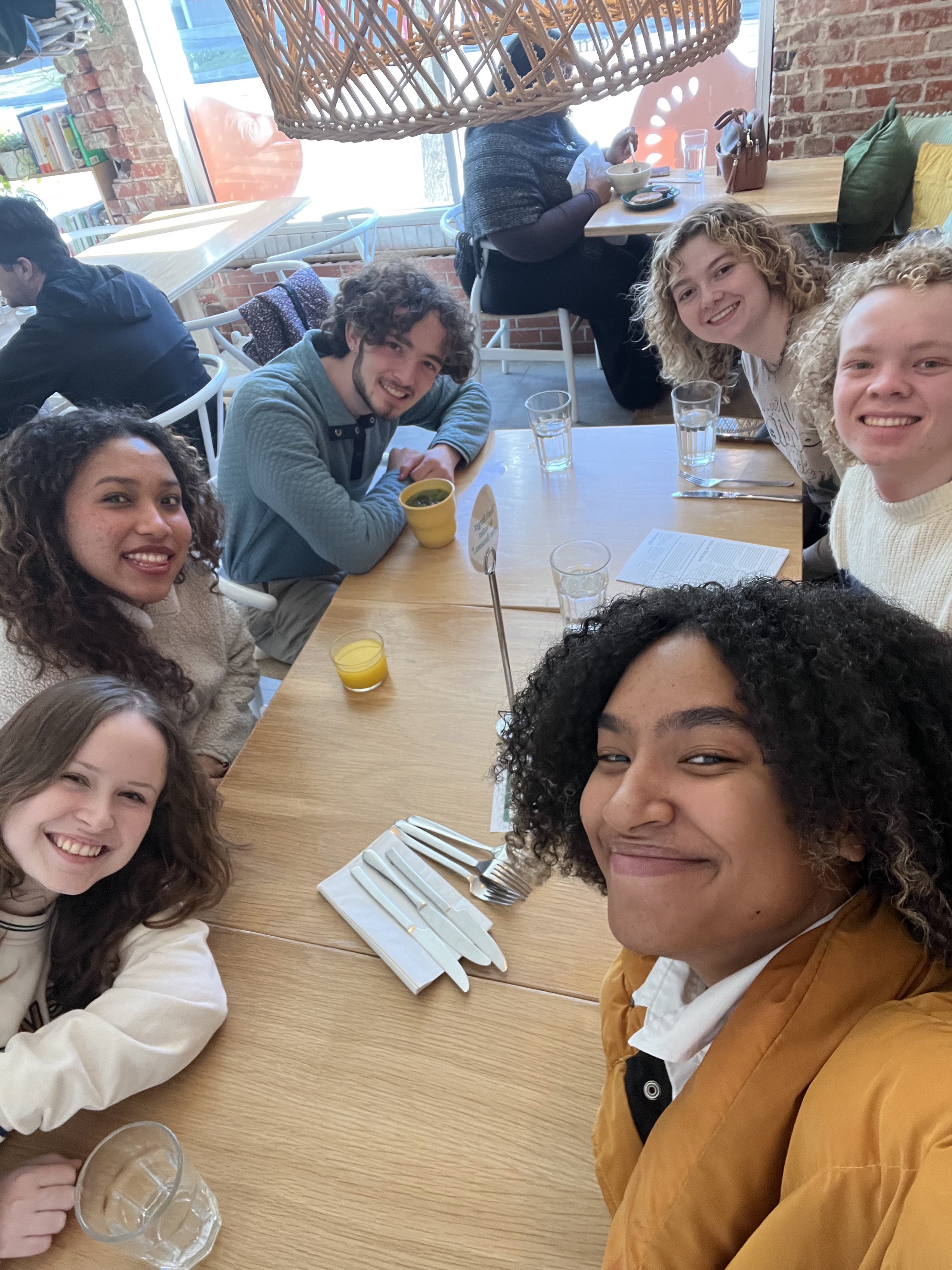 6 Alternative Break participants sitting around a restaurant table, smiling