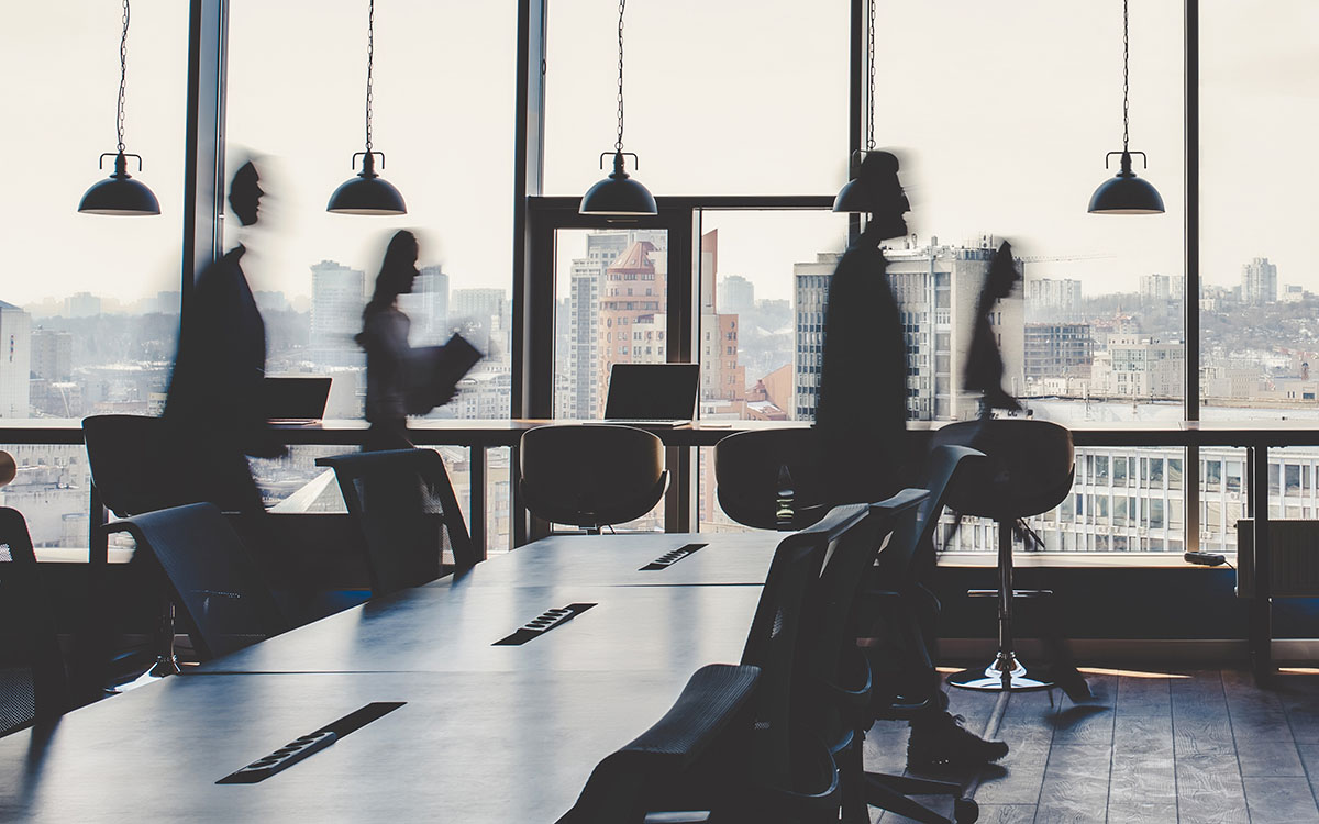 Silhouettes of individuals crossing a window overlooking the city in a workspace.