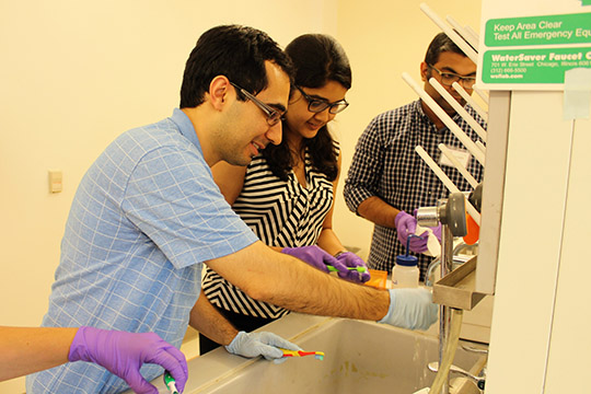 Hooman and Kavya clean their chips with toothbrushes before placing them in the sonicator.