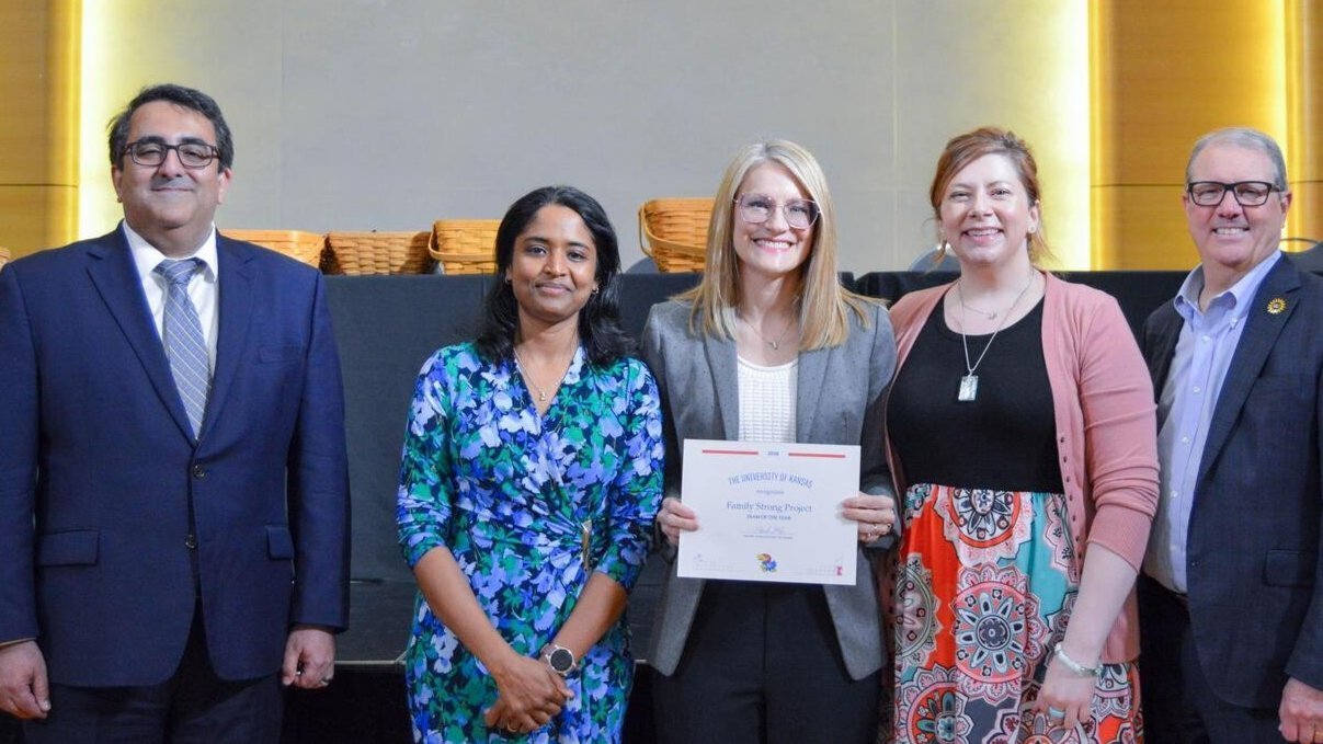 Team representatives holding an award certificate and standing with Arash Mafi and Doug Girod