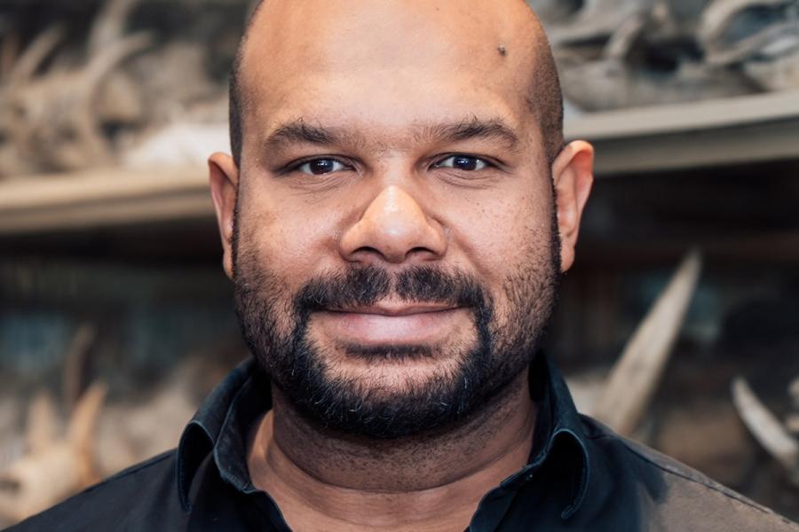 Photo of a Brandon Kilbourne in a black shirt in front of museum collections