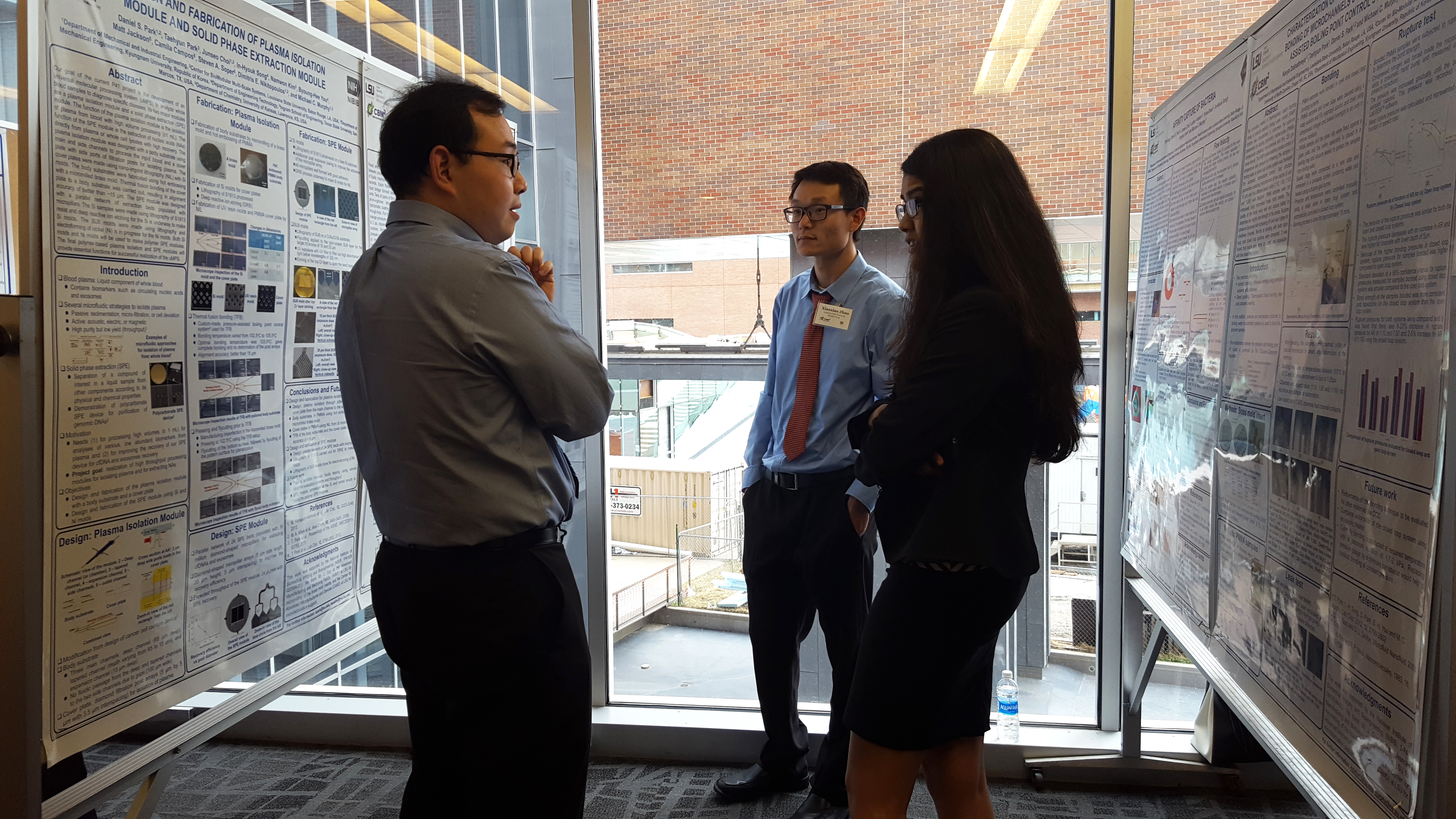 Three people conversing in the space between two displayed posters.