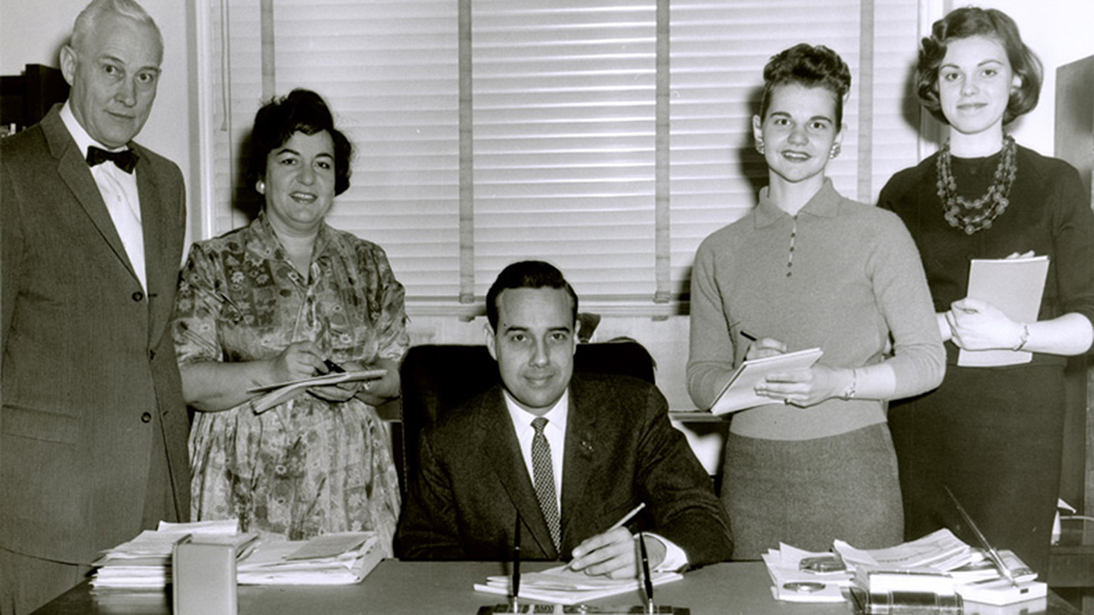 Exhibition image of Bob Dole at desk signing papers.