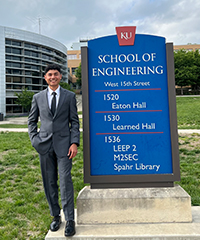 Karsh Bhatt stands next to the School of Engineering in a suit