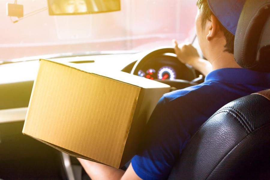 Driver making delivery holding cardboard box.