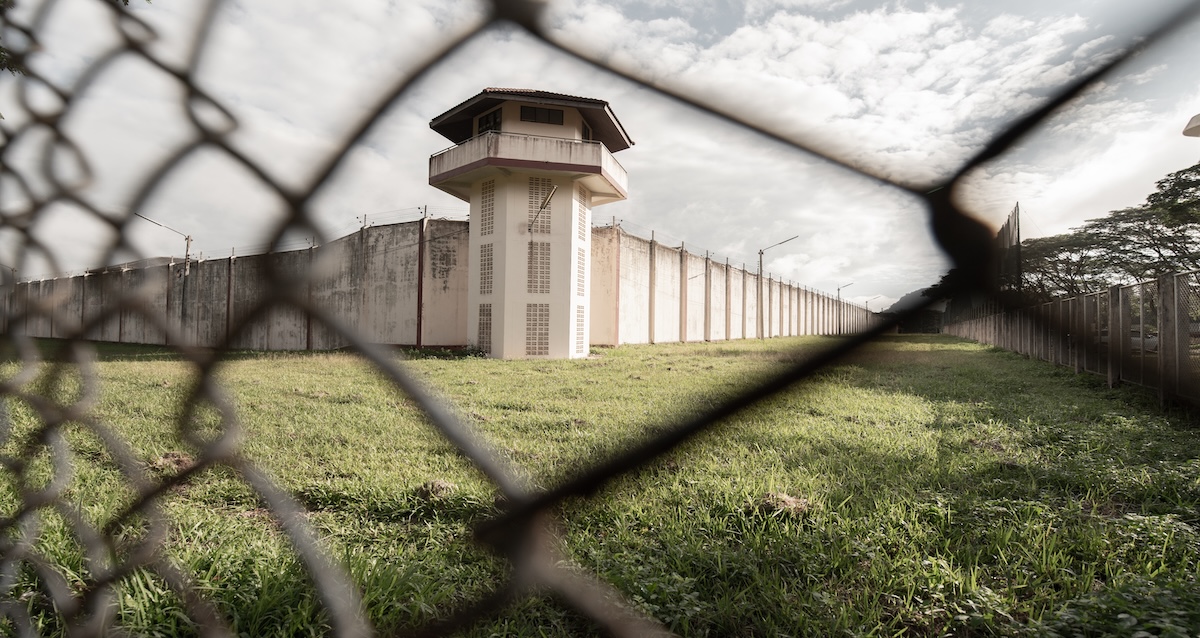 A prison tower seen from behind a fence