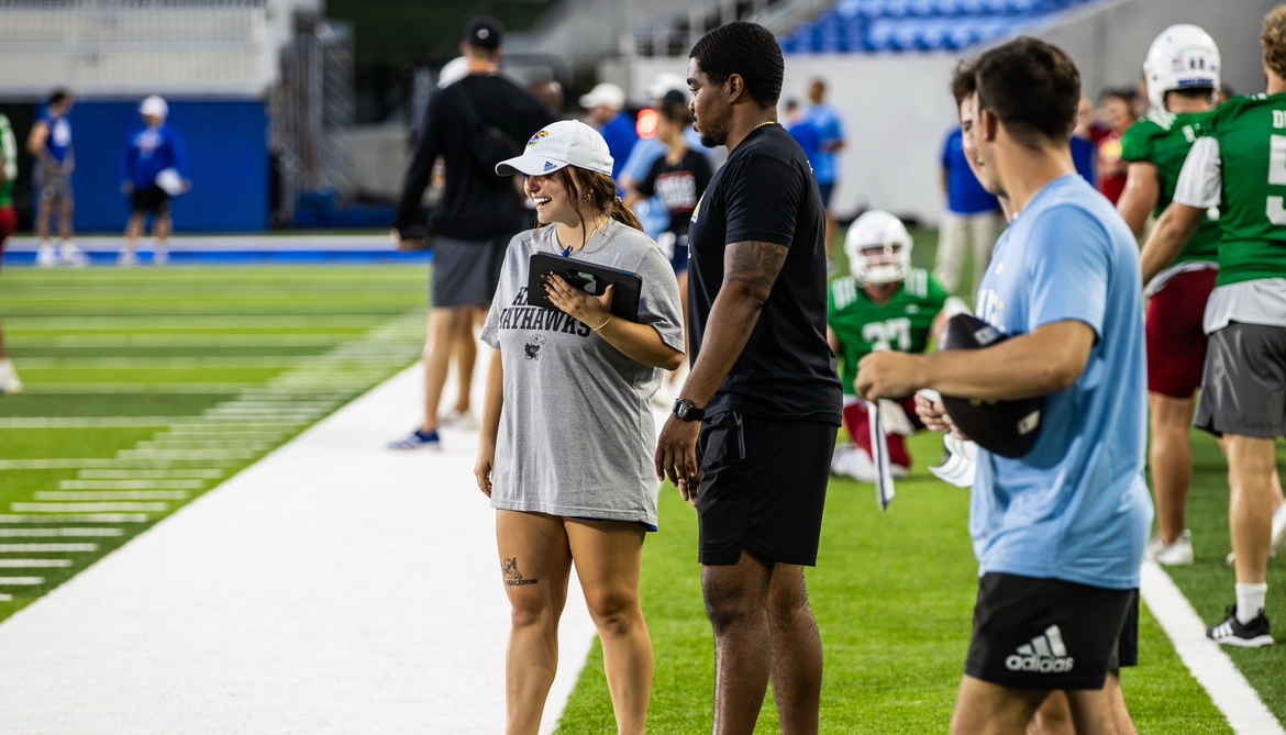 JAPL graduate research assistants and KU football interns Samuel Norwood and Madi Rink on a football field holding an iPad.