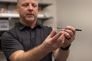 KU structural biologist Scott Lovell displaying an instrument in his laboratory