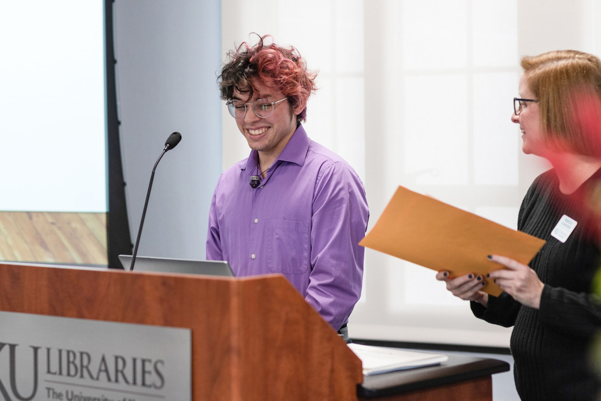 A student artist receives an award at the podium during the awards ceremony in Watson Library last fall.