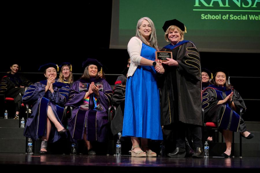 Audrey Cress receives Adjunct Teaching award from Dean Michelle Carney on stage at graduation.