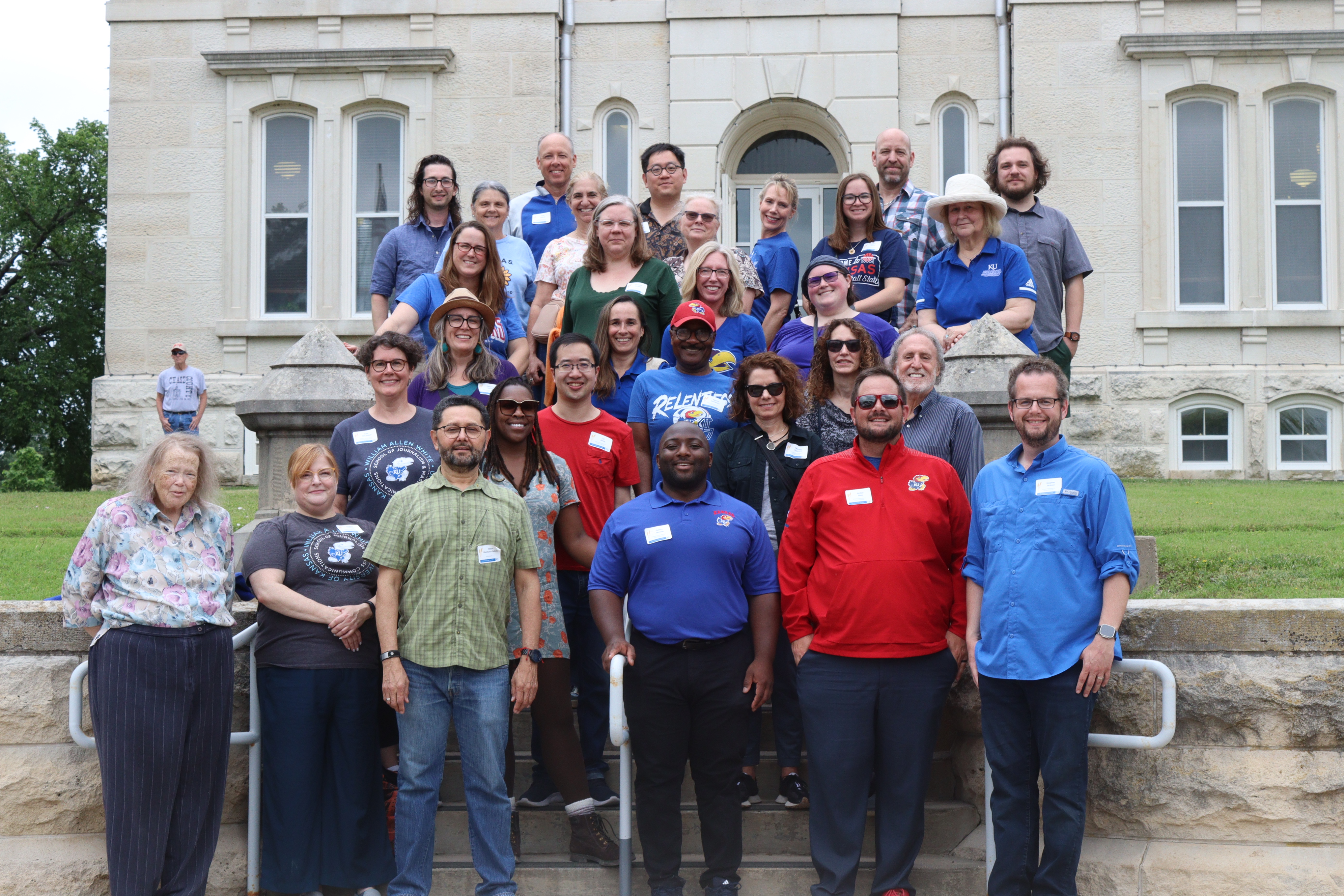 A group of faculty and staff members pose for a photo in from of a historic building