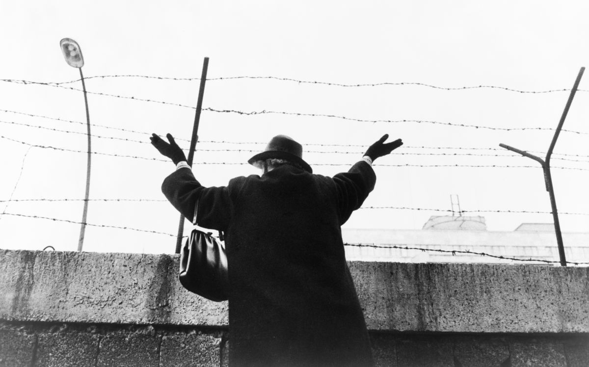 Photo: Standing at the west sector of the Berlin Wall, a woman waves at her East Berlin friends and relatives in 1961. Credit: Wikimedia Commons