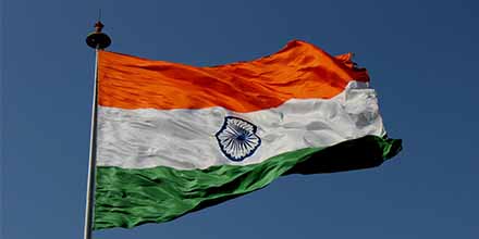 Flag of India set against blue sky.