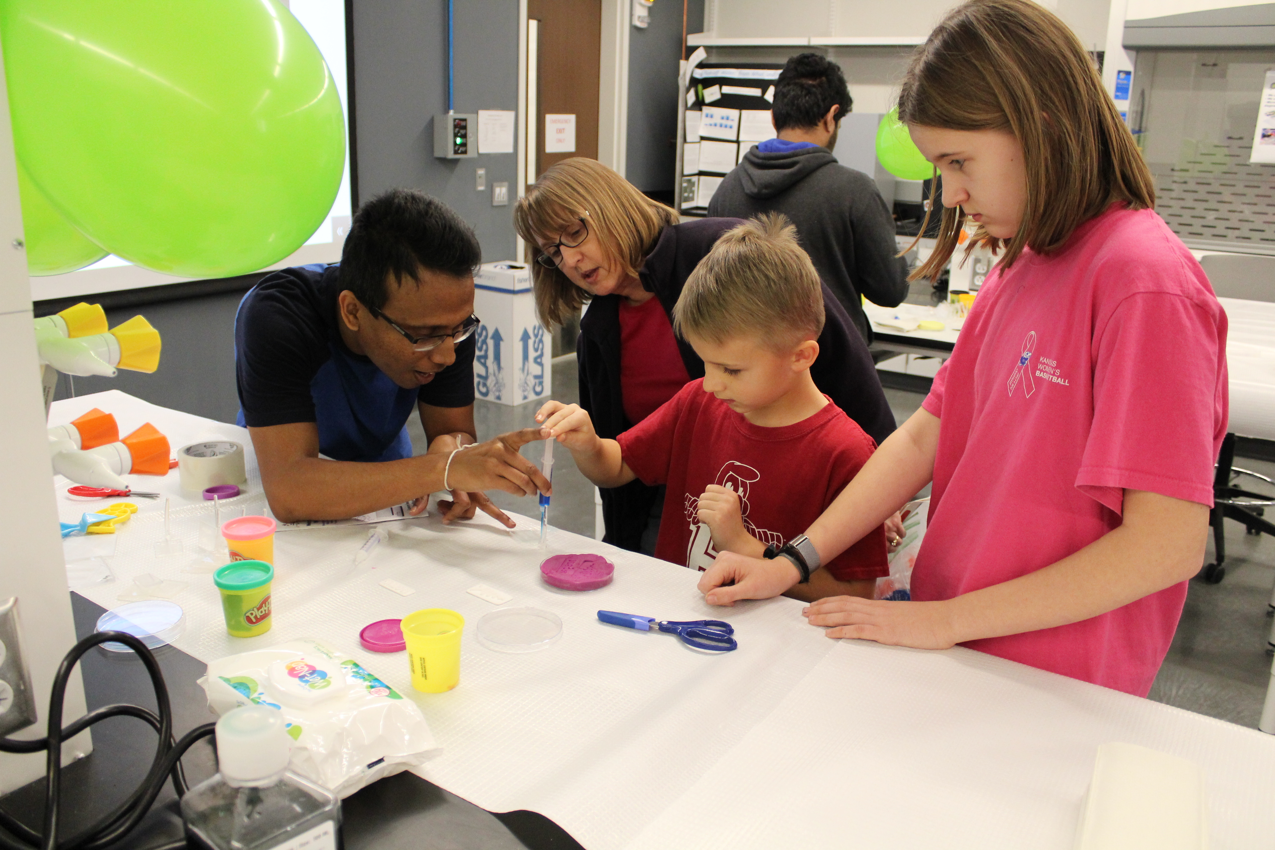 An assistant instructing a family on how to create a craft.