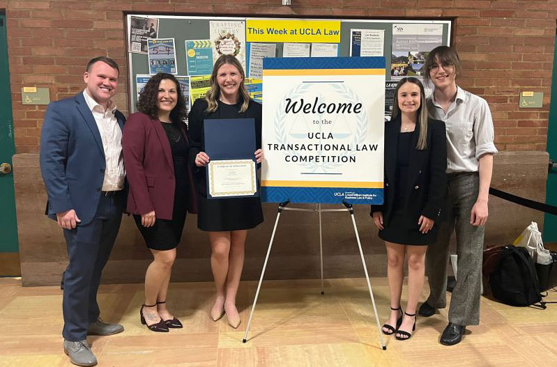 From left, standing around poster about UCLA Transactional Law meet competition, are Coach Alex Reed, Kathleen Siderchuk, Cayden Sears, Sydney Hoffman and Violet Brull.