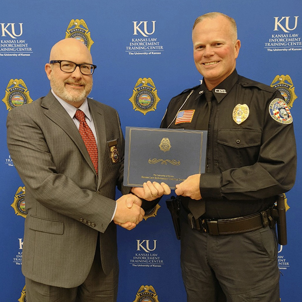 KLETC Executive Director Darin Beck shakes hands with Officer Brian Hampton, class president for the 299th Basic Training Class.
