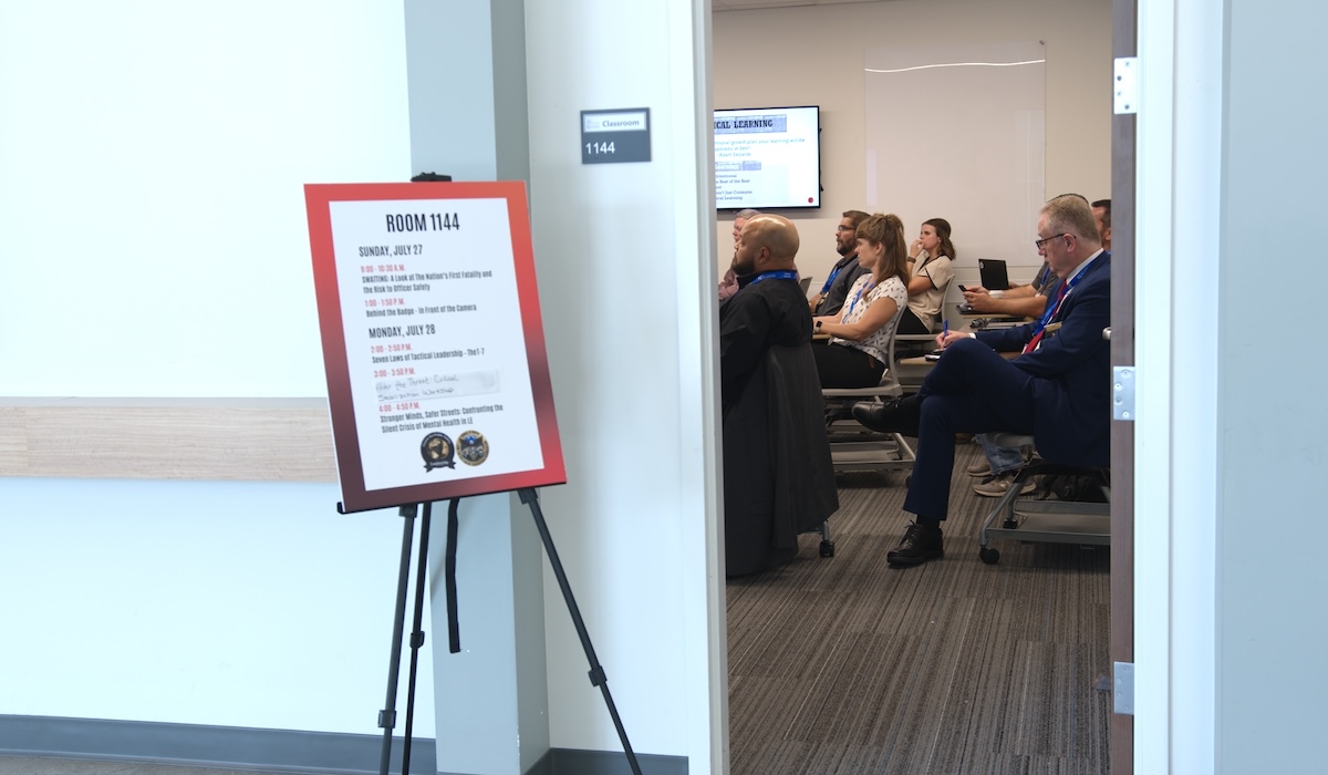 Attendees at a law enforcement conference seen through the door to a meeting room.