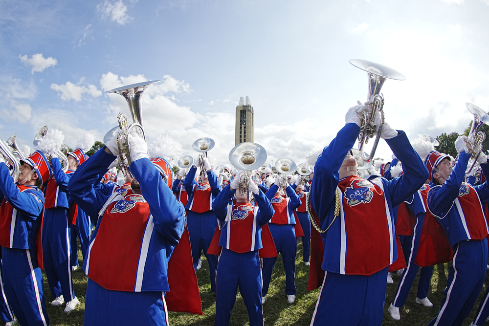 a group of musicians wearing KU Marching Band uniforms playing various brass instruments