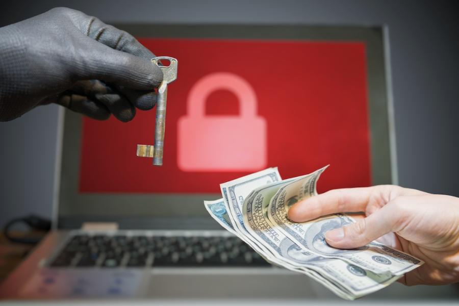 A gloved hand provides a key to a hand holding money as the image of a locked computer screen appears in the background.