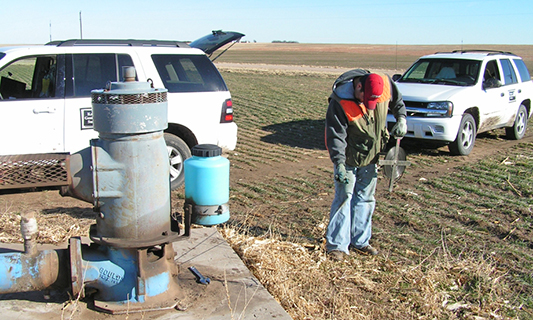 Individual measuring groundwater levels in a field