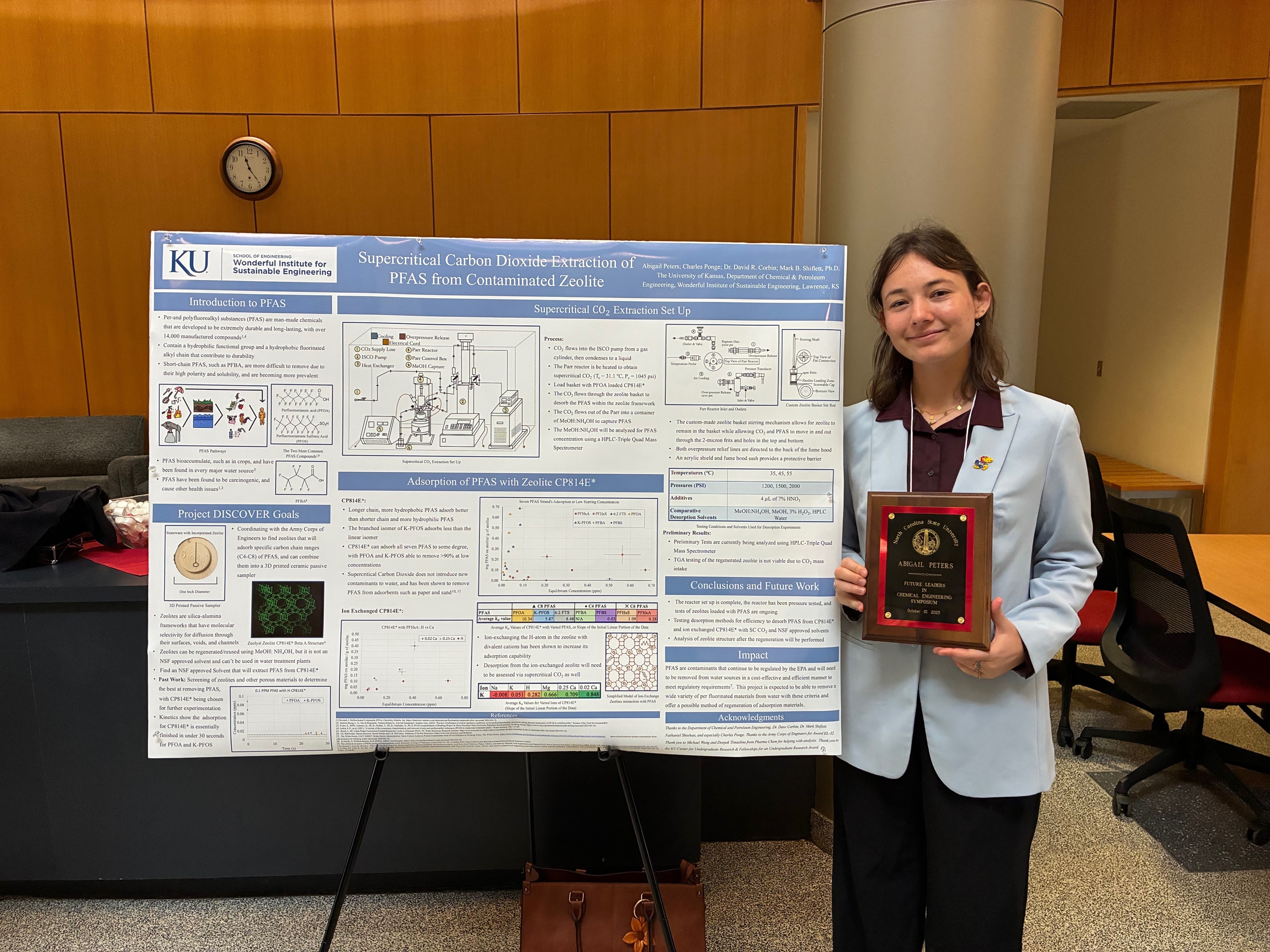 Abbie Peters stands next to her research while holding an award