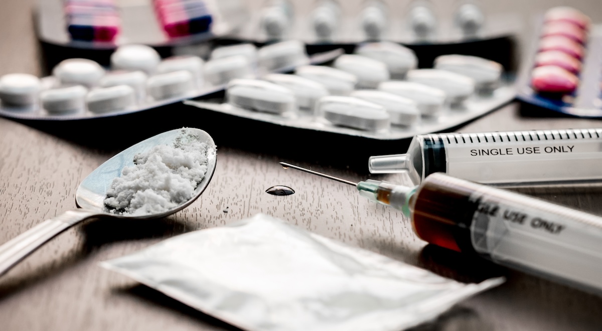 Illegal drugs and drug paraphernalia of many types litter a table.