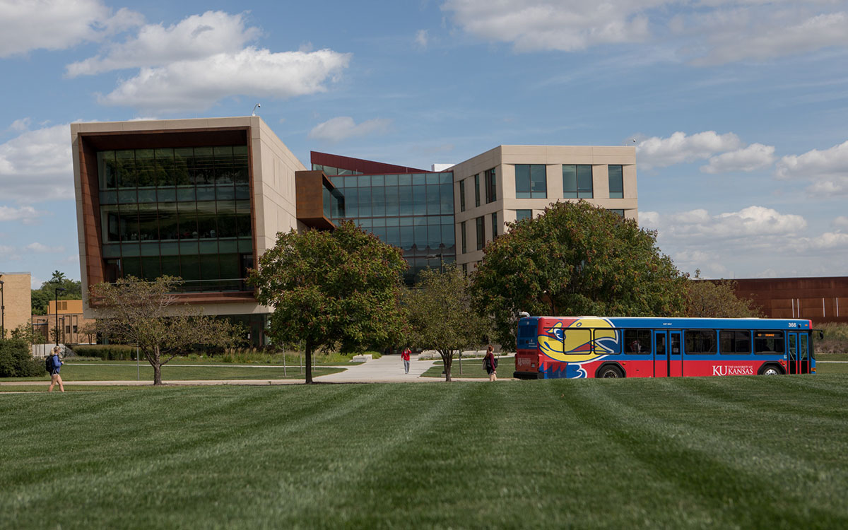 A KU bus drives down Naismith Drive in front of Capitol Federal Hall, the home of the KU School of Business.