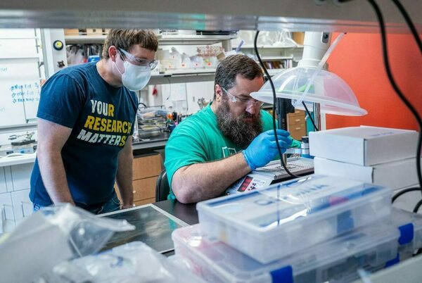 Two people talking in a lab while building sensors