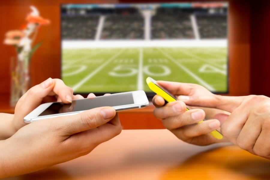 A photo shows a woman using her phone and credit card to bet on a soccer match.