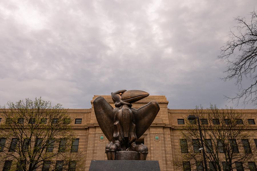 Strong Hall with academic Jay statue in front. Storm clouds in background.