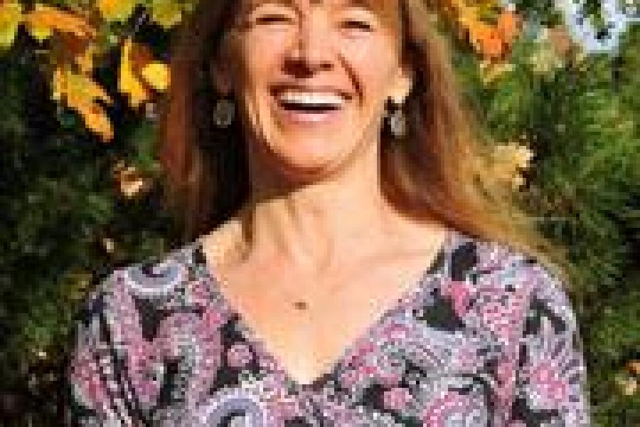 Photograph of Woman Smiling, wearing purple printed shirt.