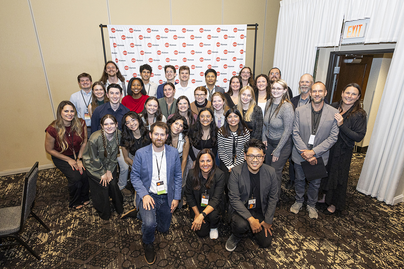 Group of KU students and instructors pose for group photograph at event in hotel conference space.