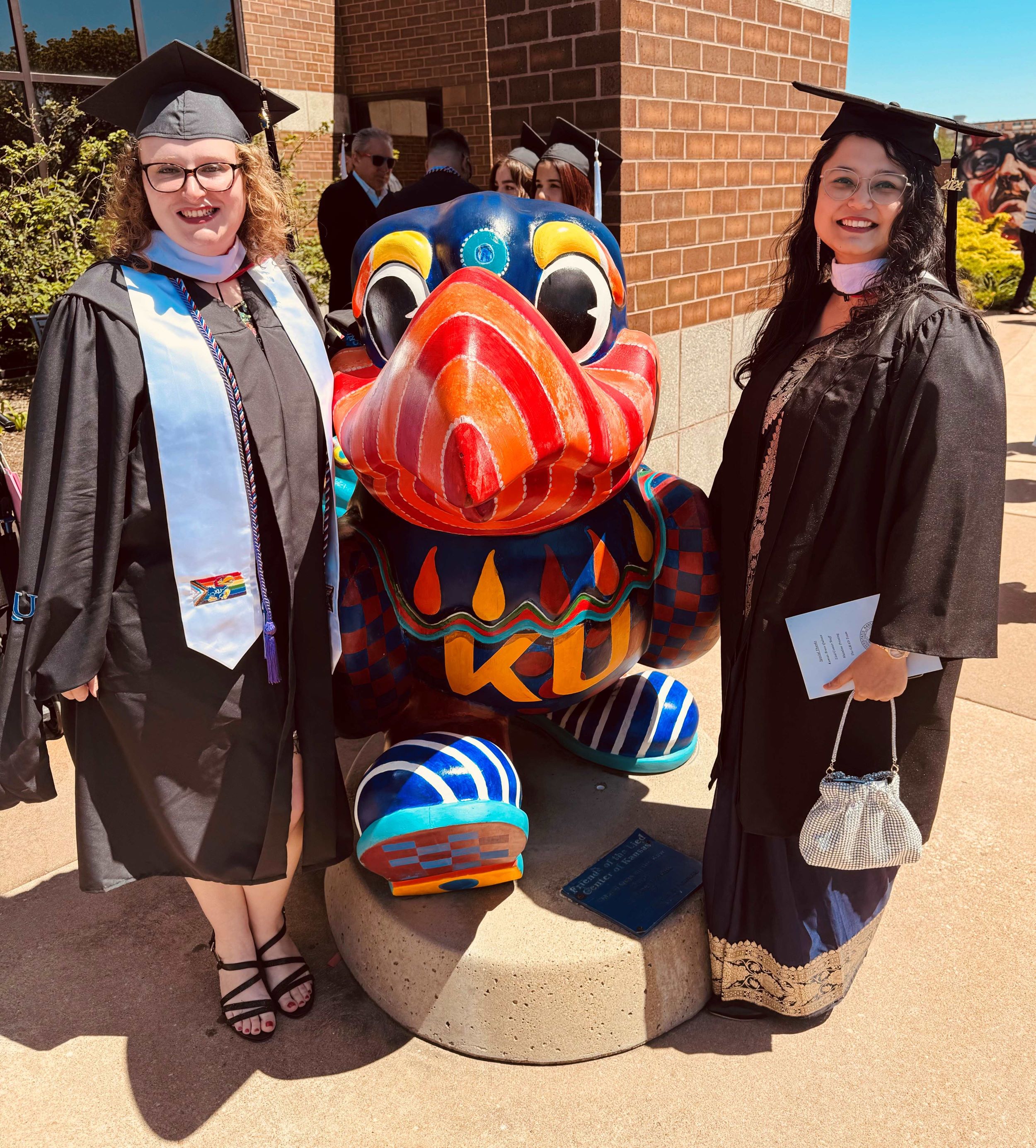 photo of two individuals posing by jayhawk