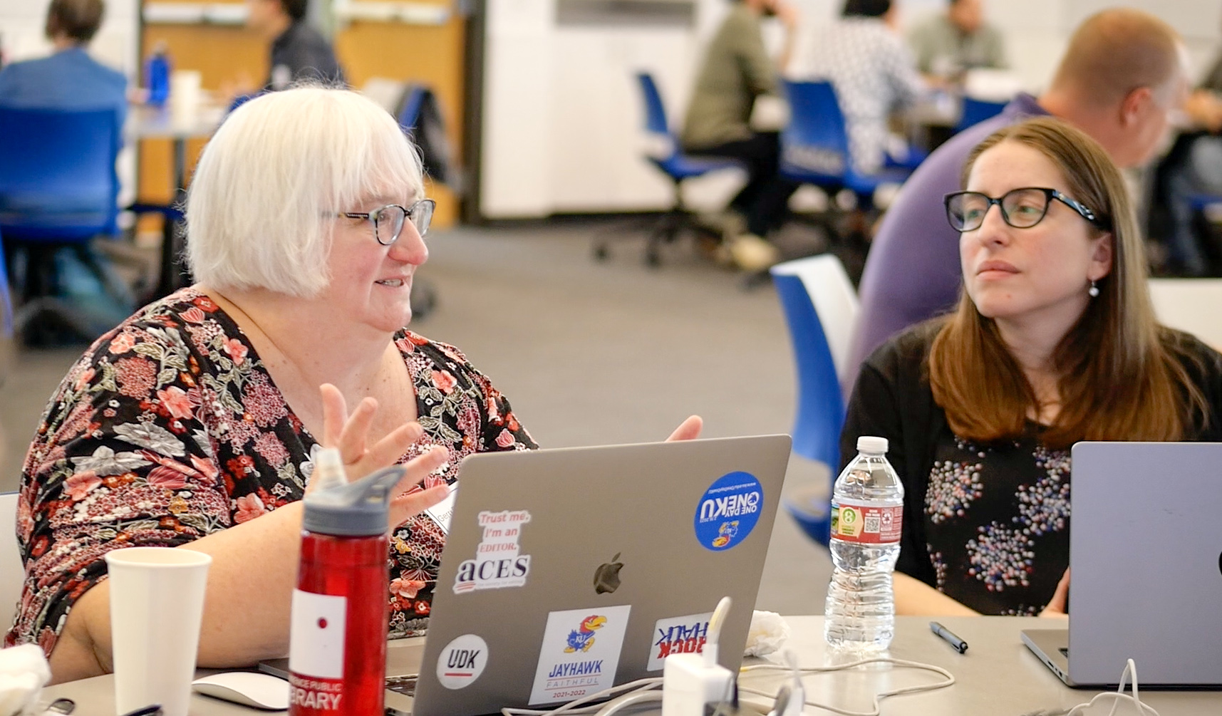 Two womens sitting at a table one with a laptop in front of her.