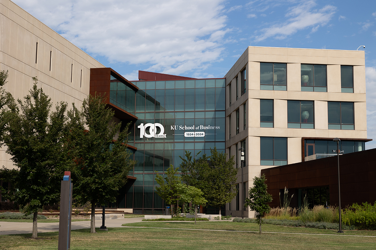 The exterior of Capitol Federal Hall, home of the KU School of Business, with a "100 years, KU School of Business" decal seen on a third story window