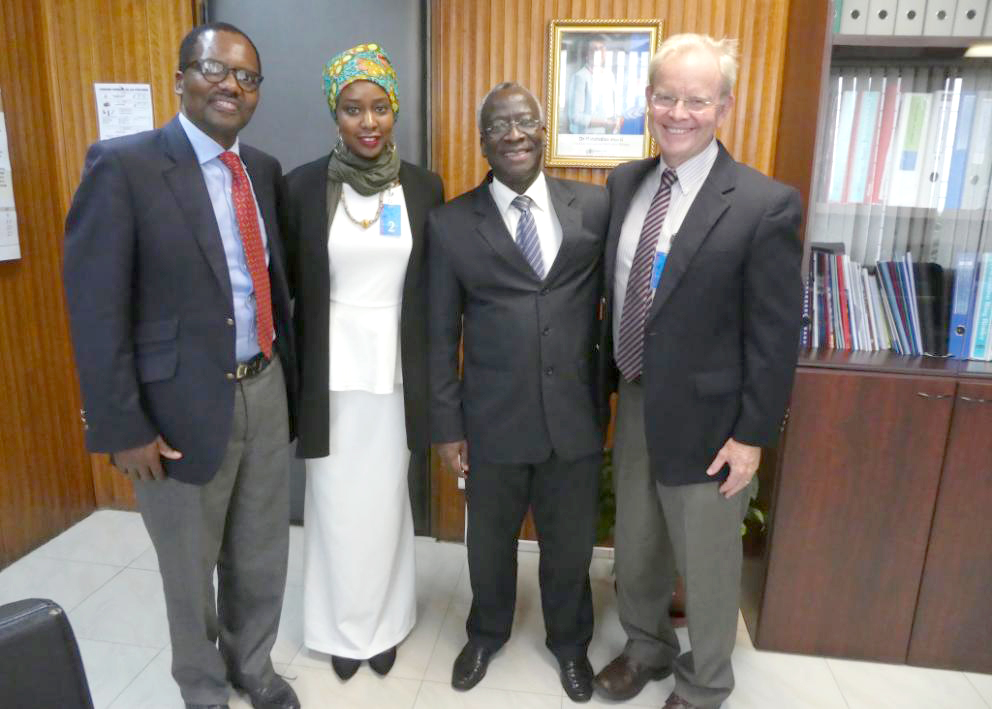 Four adults stand for a photo an an office