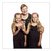 Photo of smiling woman with two girls, all wearing black clothing.