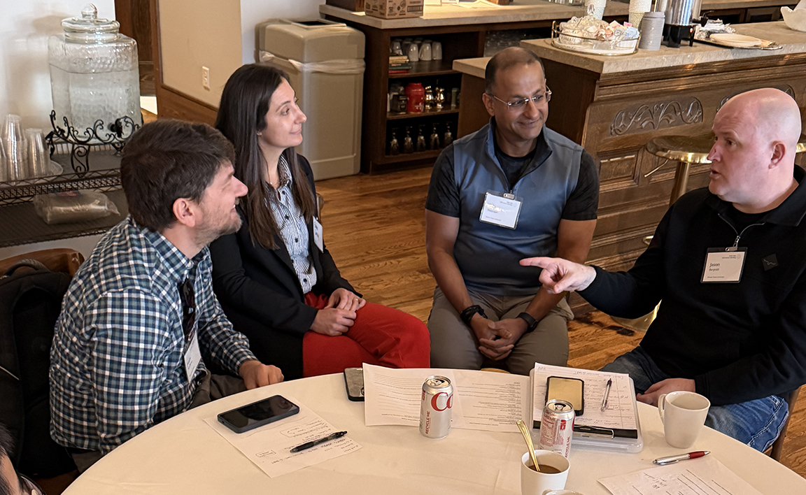 Four faculty members talk at a table