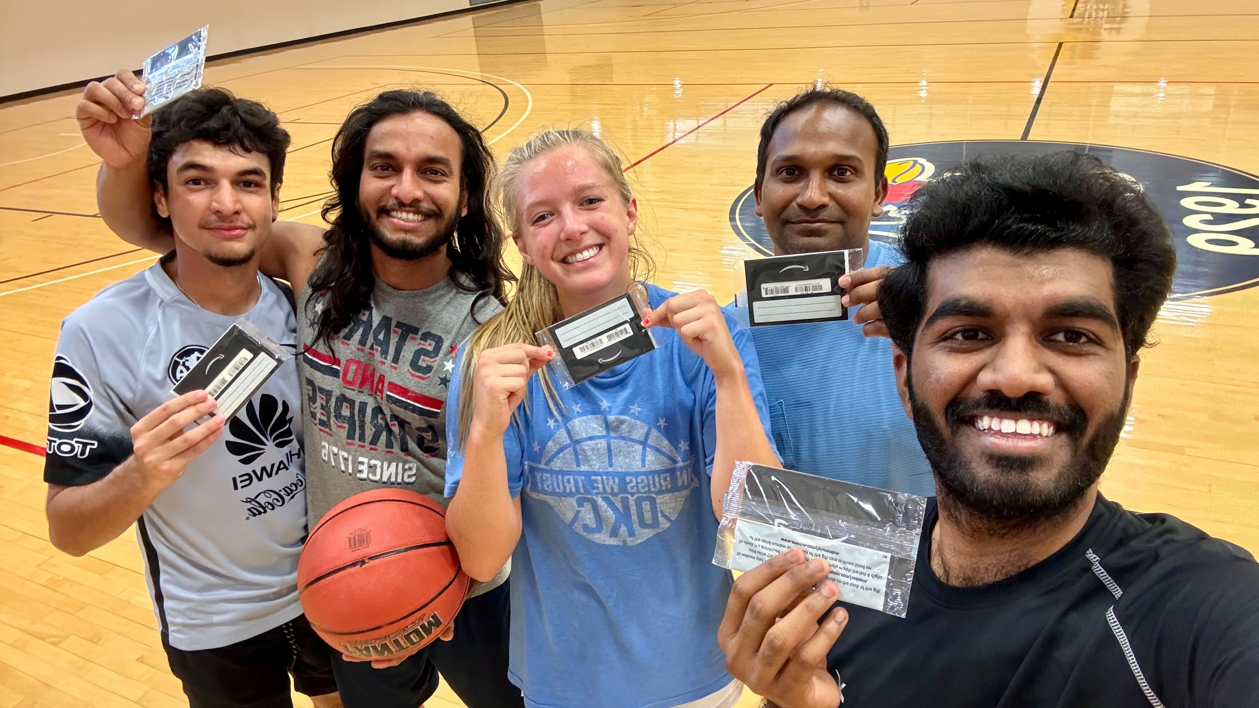 Group of people on a basketball court, smiling at the camera