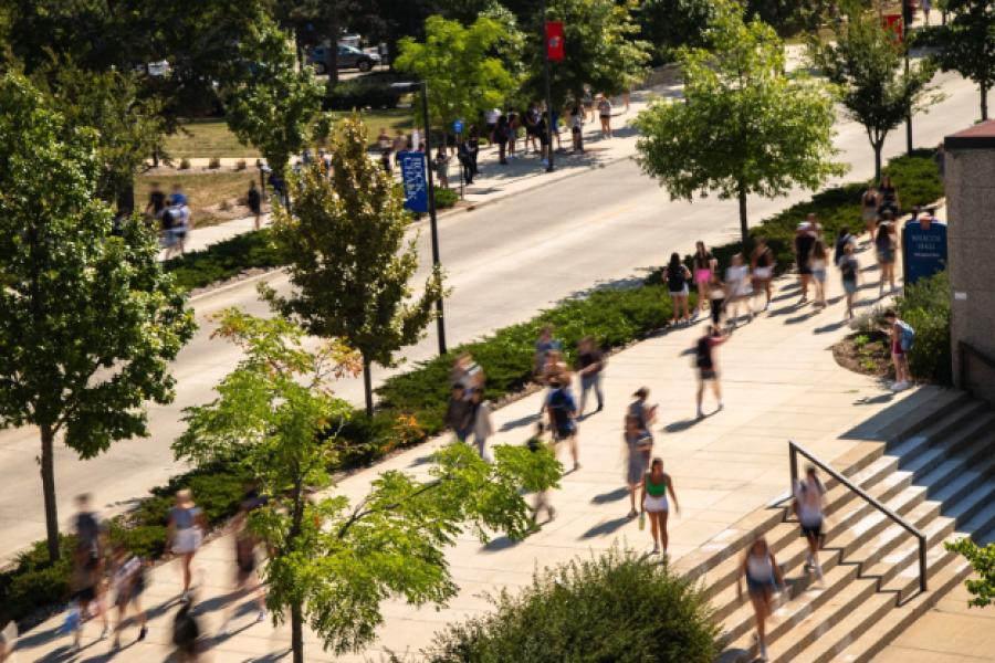 Students cross Wescoe Beach on a sunny day at the University of Kansas campus.