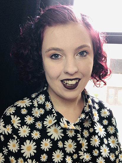 Tiffani Brooks Hagan with cherry red hair and blouse with daisies on it. 