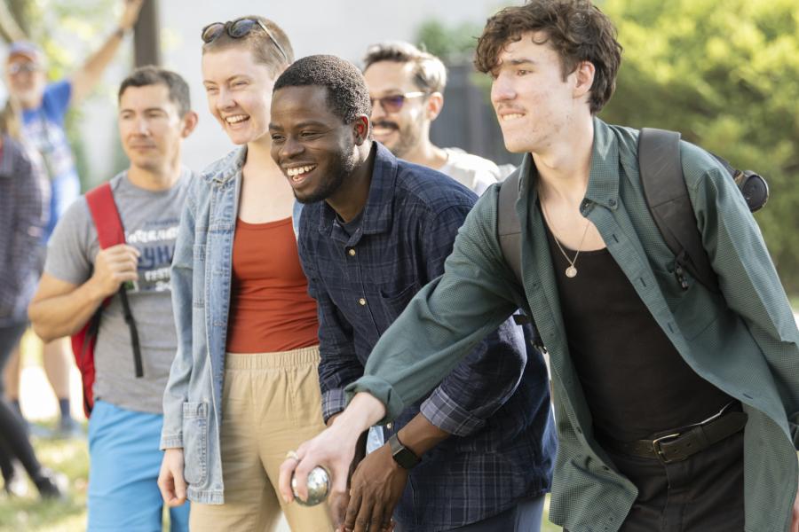 Students smile and play bocce on the front lawn of Watson Library