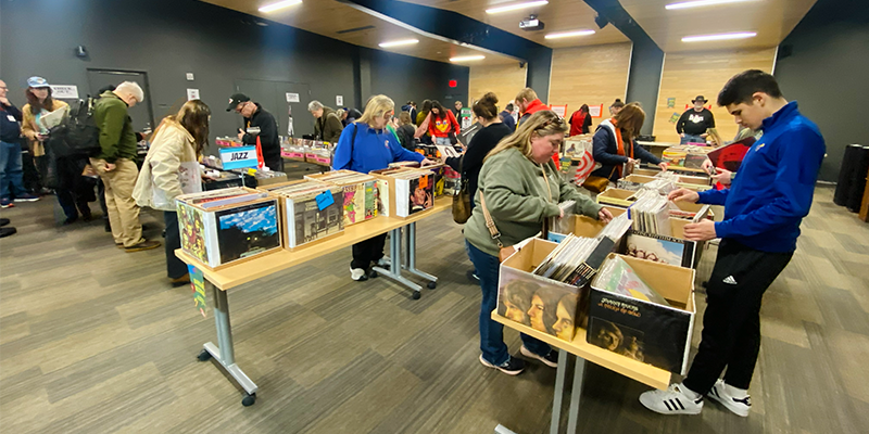 Two dozen people look through boxes filled with records at the Lawrence Library.