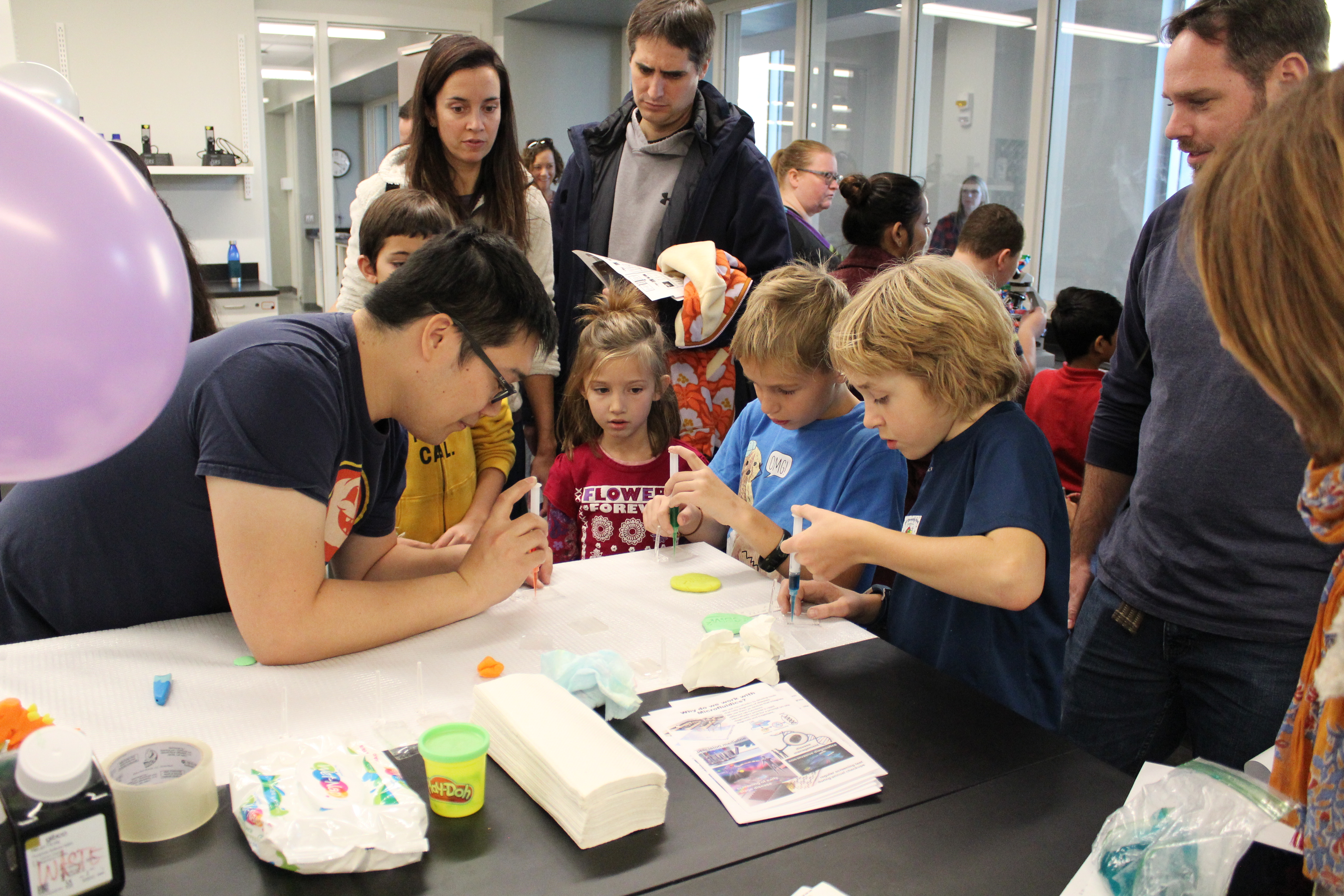 A group of individuals injecting colored liquids into chemistry glassware.