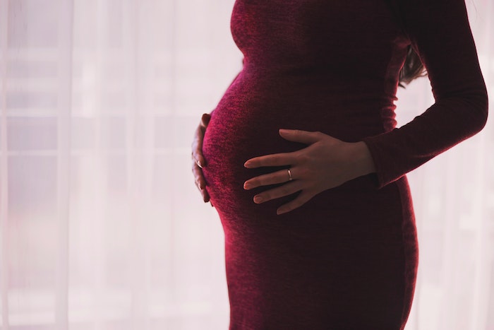 Pregnant woman holding stomach. Pexels.com