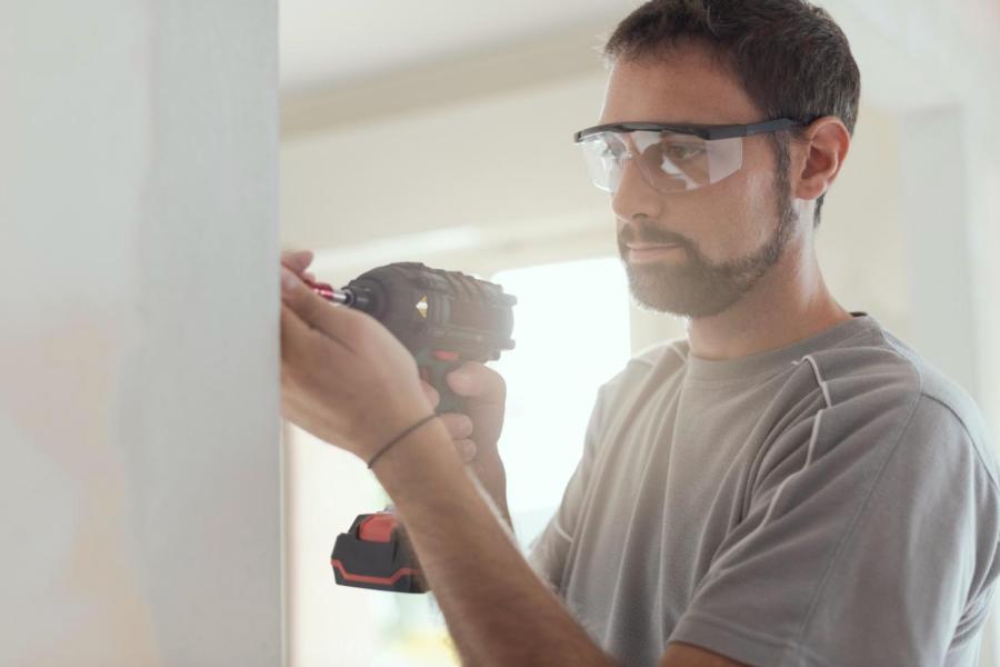 Man wearing protective eyewear while using electric drill