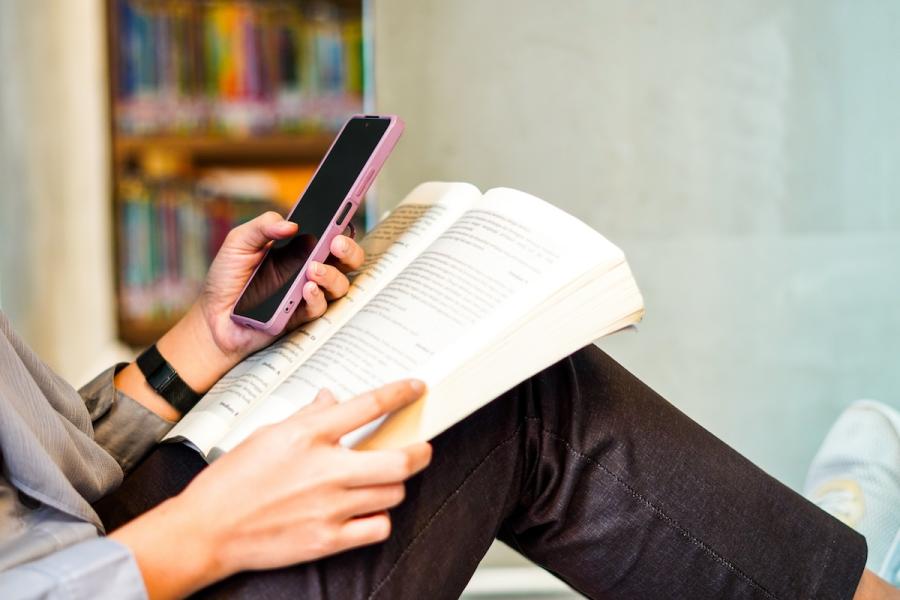 Stock photo of woman using phone in library setting