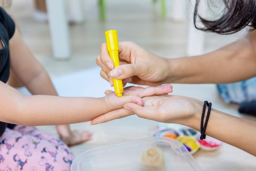 Chid and caregiver's hands in daycare setting.